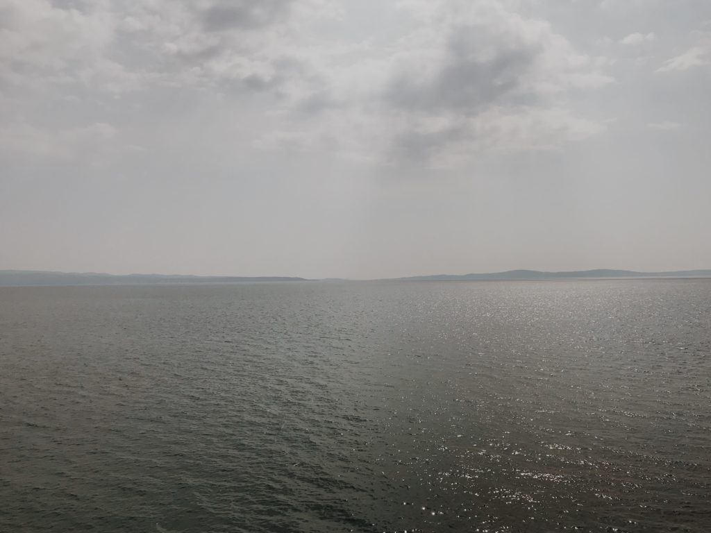 View of open dark blue sea with Italy in the background