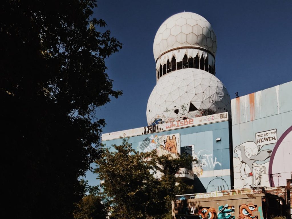 An empty building and geodesic dome at the listening station are covered with various murals